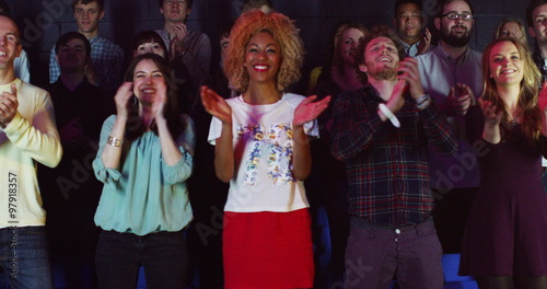  Young theatre audience give a standing ovation to the performers on stage photo