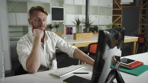 A pleased businessman sittingin his office working at his computer. photo