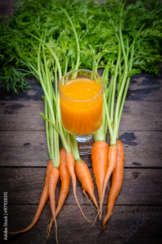 Fresh-squeezed carrot juice on wooden background