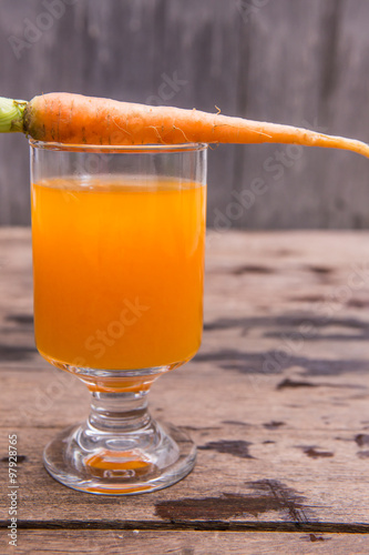Fresh-squeezed carrot juice on wooden background