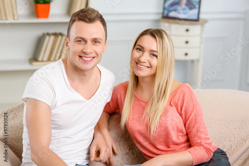 Young smiling couple sitting on the sofa.