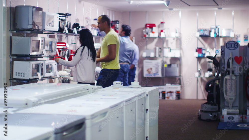 Couple shopping in a shop selling fridges and washing machines dishwashers and kitchen products. 
