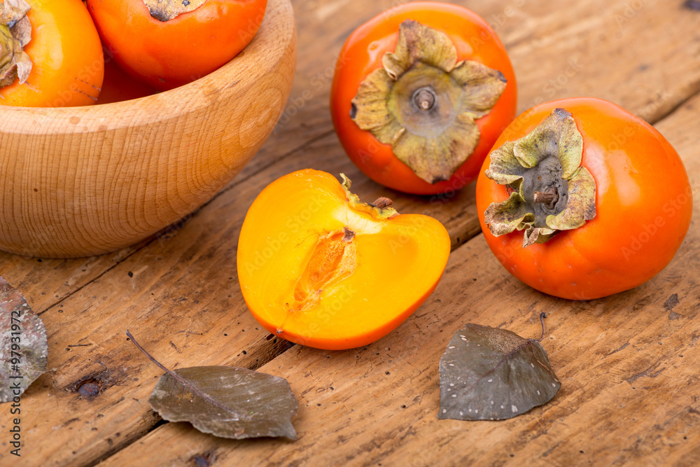 Fresh ripe persimmon on a wooden table - selective focus Fresh ripe persimmon on a wooden table - selective focus