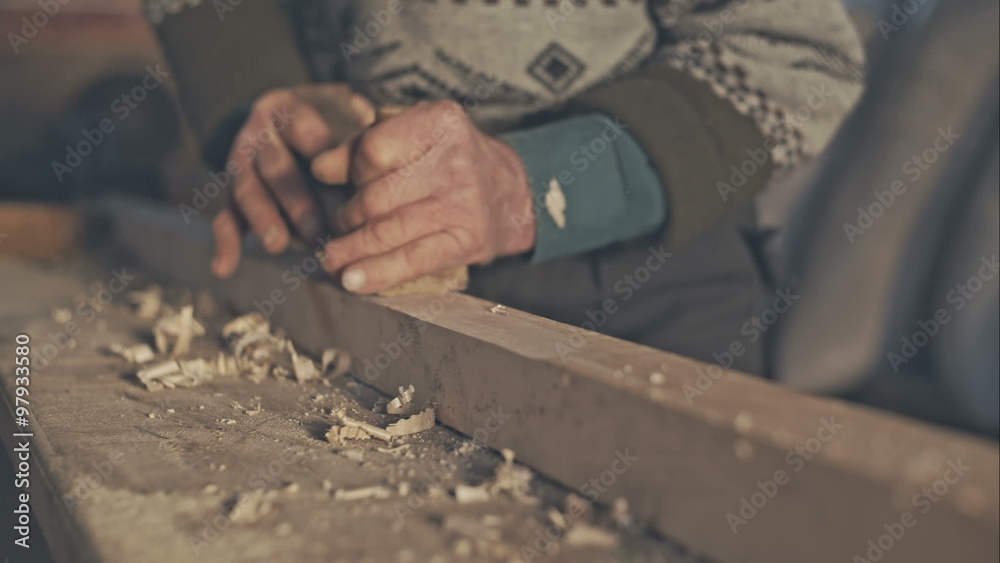 Senior craftsman working with planer on wooden pole in his workshop