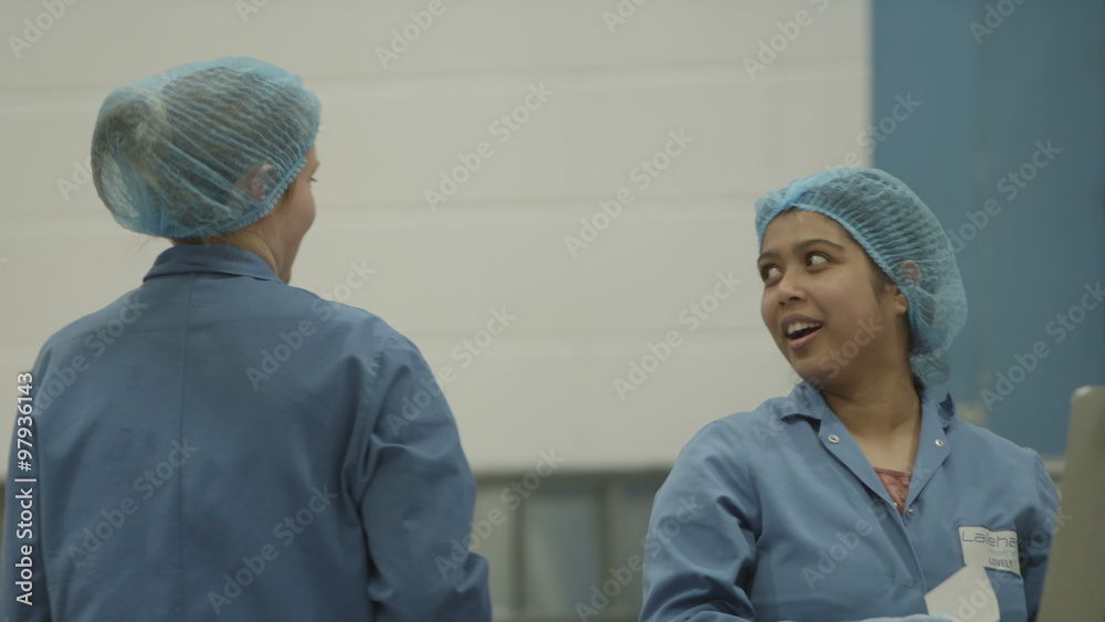 Two woman factory workers smiling and working as a team