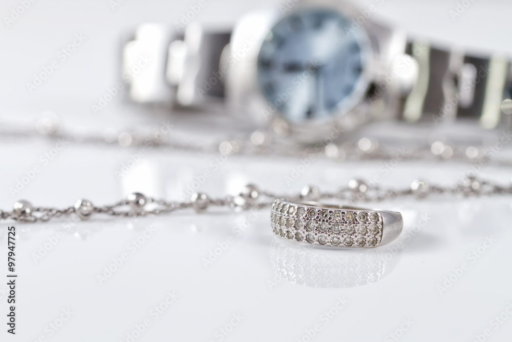 Silver ring and chain on the background of watches Silver ring and chain on the background of watches