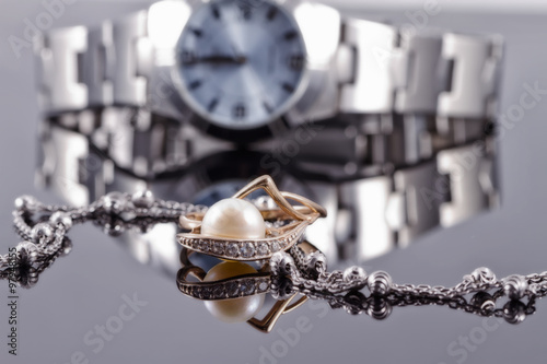 Gold ring with pearls and silver chain on the background watches