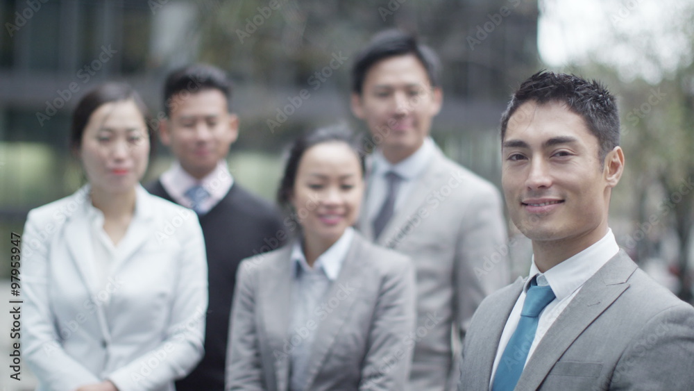 Portrait of smiling Asian businessman outdoors in the city with his team Portrait of smiling Asian businessman outdoors in the city with his team