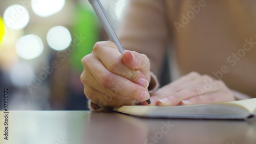 Close-up of female hands writing in a diary photo