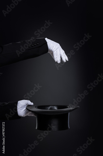 Magicianˈs hands in white gloves with top hat photo