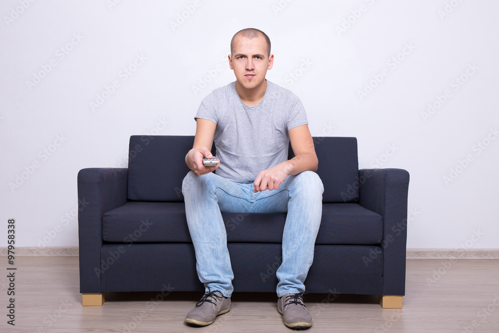 young man sitting on sofa and watching tv at home