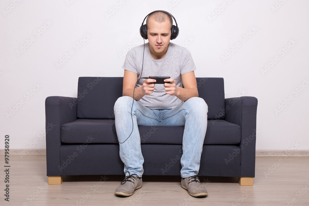 man on couch playing games or watching movie on mobile phone man on couch playing games or watching movie on mobile phone