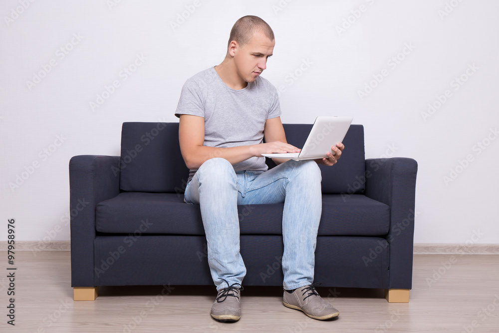 handsome man sitting on sofa and using laptop