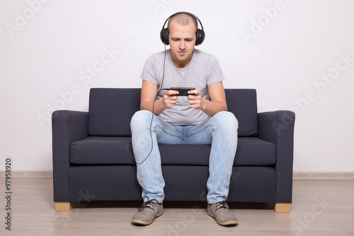 man on couch playing games or watching movie on mobile phone