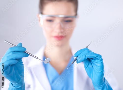 Attractive female dentist with tools , standing on gay background