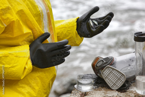 Photography scientist in mask and protective uniform examining  little fishes on hand in glo