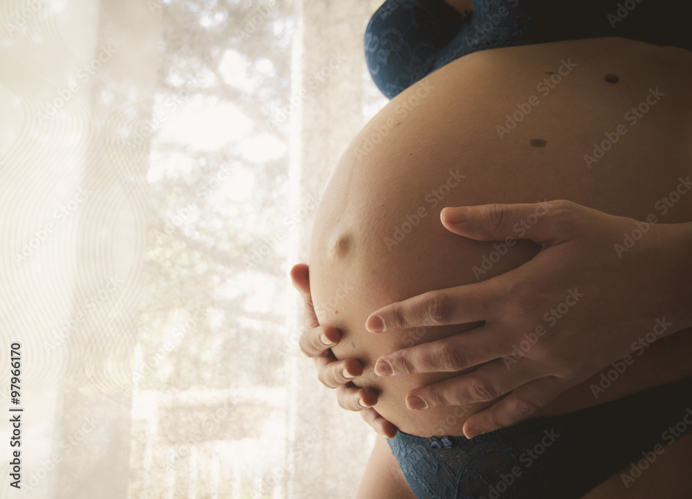Foto Stock Donna incinta che accarezza il suo pancione durante la  gravidanza