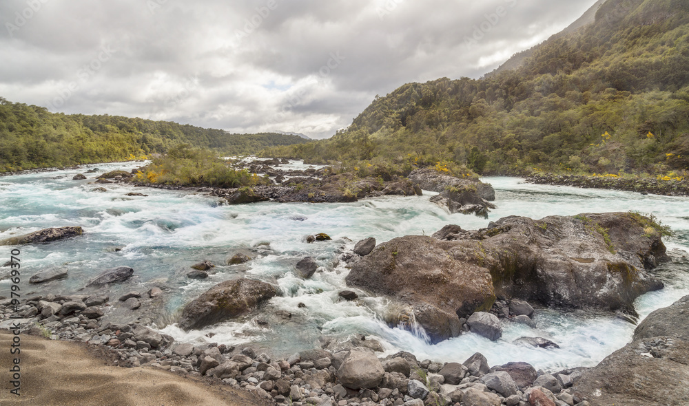Mountain fast flowing river stream of water in the rocks with cloudy sky Mountain fast flowing river stream of water in the rocks with cloudy sky