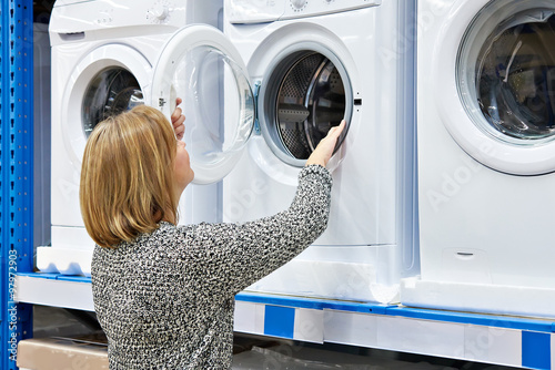 Woman housewife chooses washing machine in shop of home applianc photo