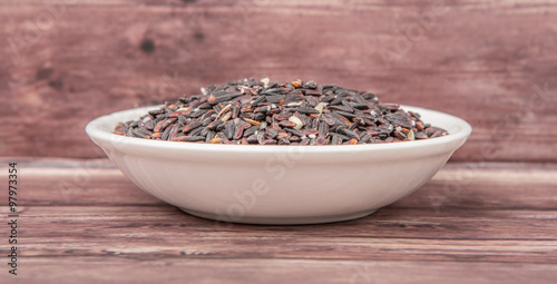 Black glutinous rice in wooden bowl over wooden backgound