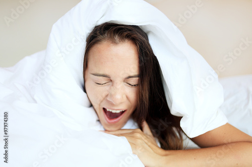 Beautiful girl yawning in bed after sleeping