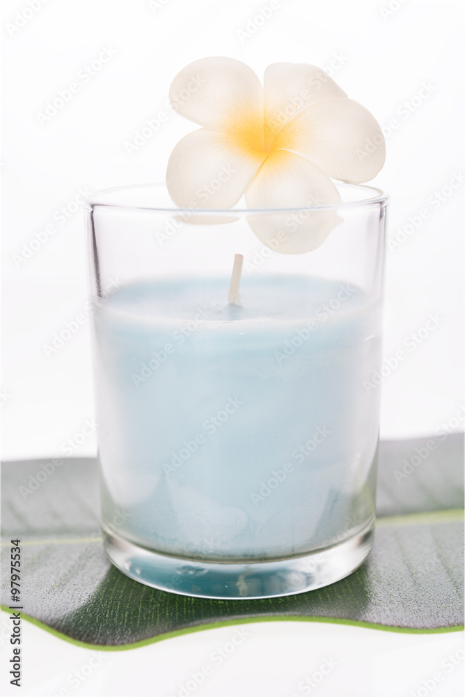 A blue candle in glass and frangipani flower isolated on white b A blue candle in glass and frangipani flower isolated on white b