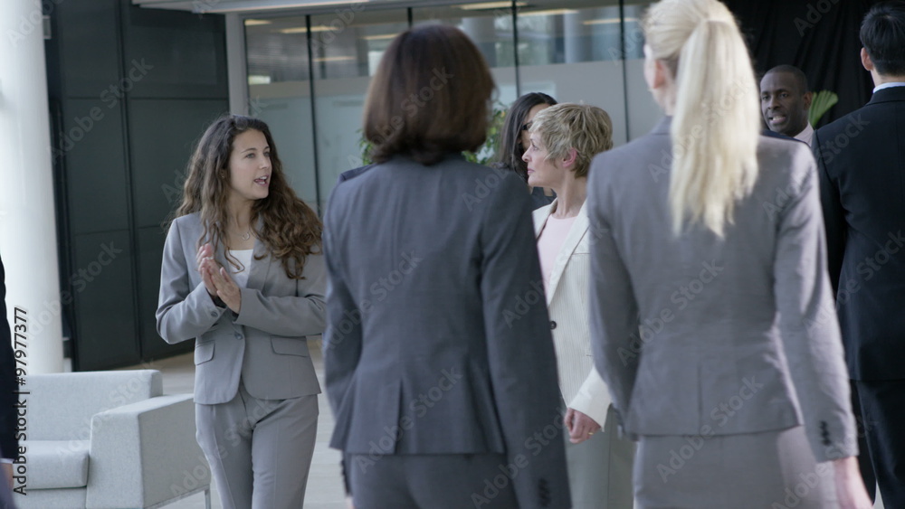 Large diverse business group talking as they walk through office building Large diverse business group talking as they walk through office building