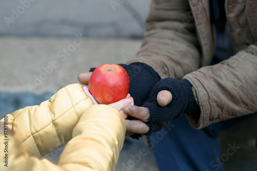Child gives apple to the beggar.  photo