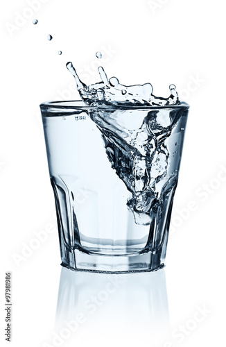 Ice cubes splashing into glass of water