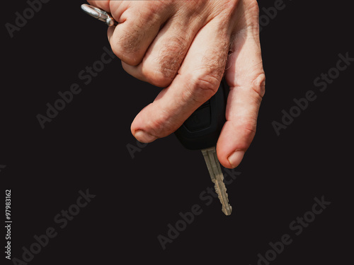 hand with car key on black.