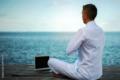 Obraz na płótnie businessman has a yoga practice with a laptop on a wooden bridge w salonie