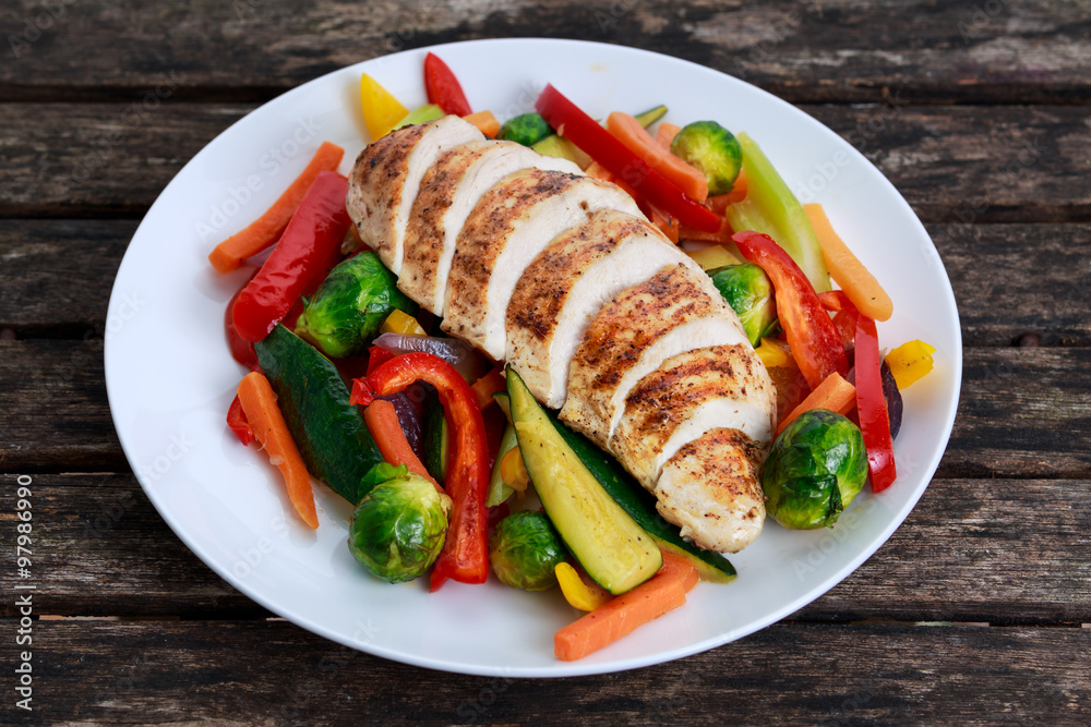 Grilled chicken fillet, breast with cooked vegetable on plates. Grilled chicken fillet, breast with cooked vegetable on plates.