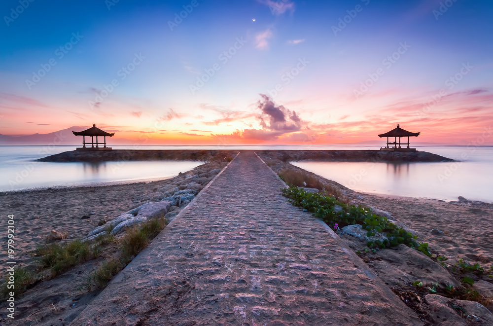Beautiful image of nature landscape with stone walkway by the beach at sunrise. Visible noise due to long exposure shot.
