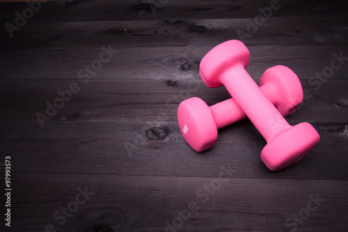 Sport equipment. Pink dumbbell on a black wooden background