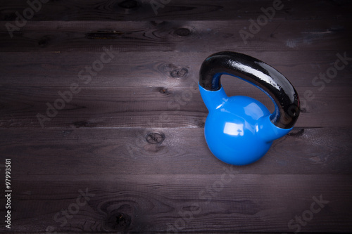 Sport equipment. Blue kettle bell on a black wooden background
