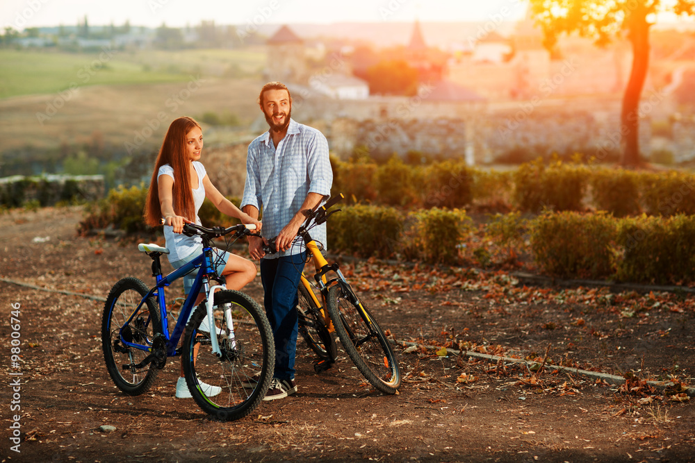 Fototapeta premium happy young couple of bicyclists talking in the street