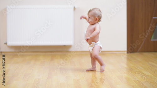 Baby making his first steps on the floor at home photo