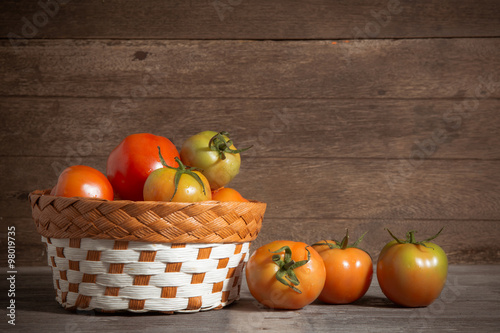 juicy red tomatoes in basket on wooden table