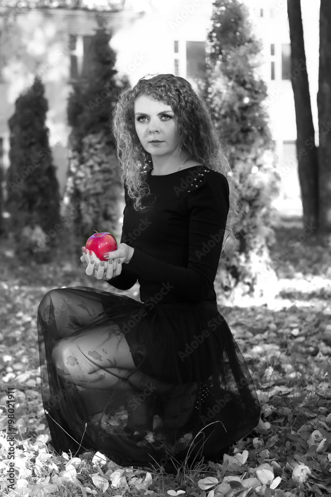 The girl in a black dress with red apple in bw