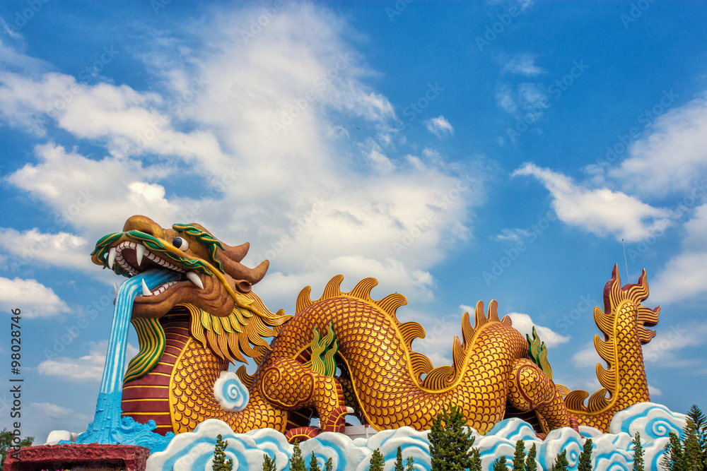 Fototapeta premium Large golden dragon statue on sky background
