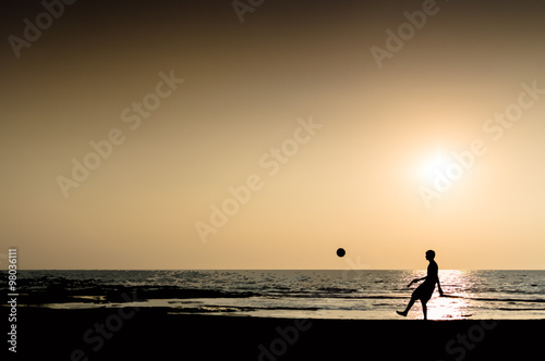 Young man playing football silhouette ocean horizon sunset horiz