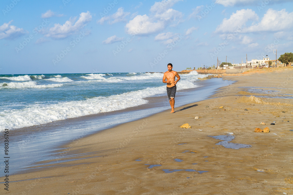 Young man in his twenties jogging on a sandy beach