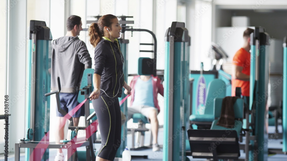  woman skipping in the gym with group of men using the machines in background