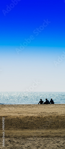 Vertical three freinds sitting on the ocean beach background bac