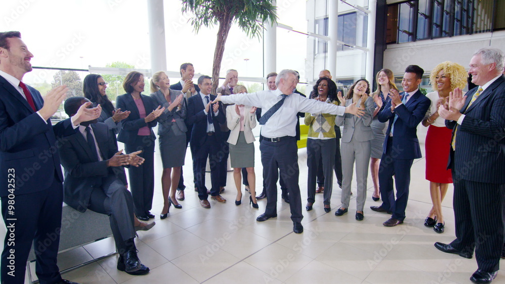 Self confident businessman cheering and giving high fives to colleagues as the rest of the team applaud and smile Self confident businessman cheering and giving high fives to colleagues as the rest of the team applaud and smile