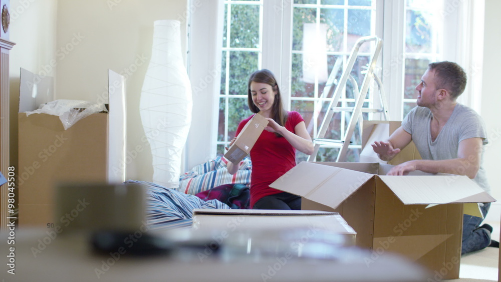 Happy young couple unpacking boxes, moving into new home Happy young couple unpacking boxes, moving into new home