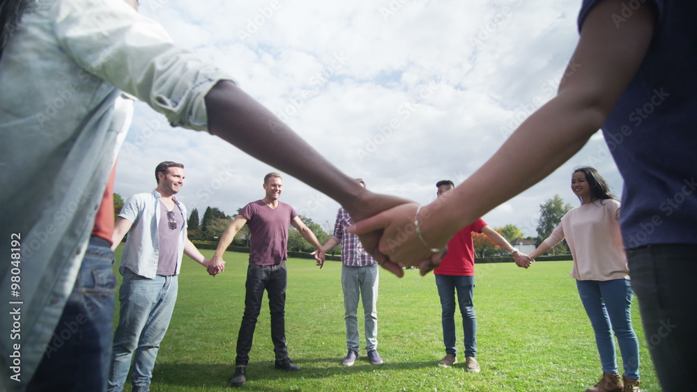  Happy Christian friends outdoors standing in a circle and holding hands