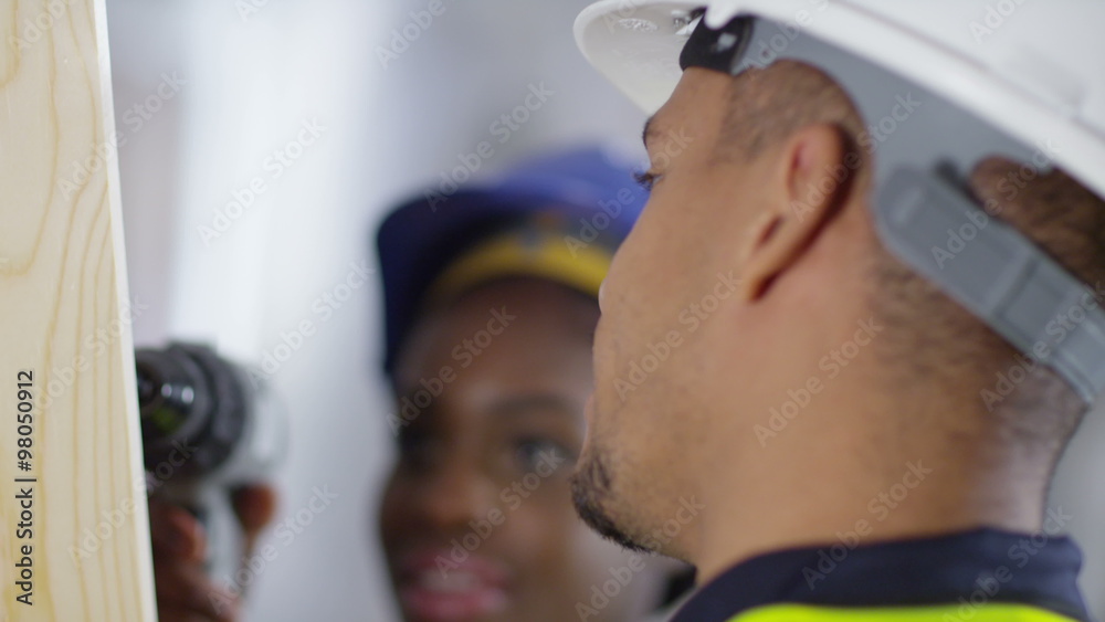 Male construction worker or tradesman working with female apprentice, showing her how to use a drill. Male construction worker or tradesman working with female apprentice, showing her how to use a drill.