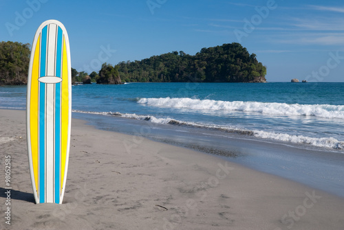 Photography Yellow , blue and white surfboard (off center) on a beach in Costa Rica