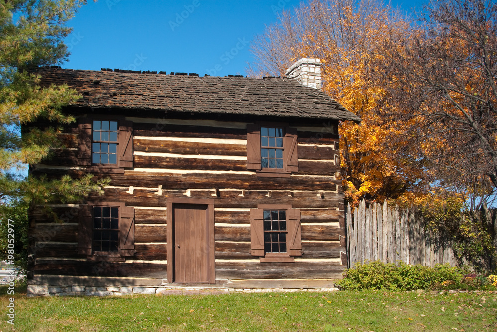 Obraz premium Rustic fall setting of old log cabin with pumpkins, gourds, indian Corn, plant and flowers on bails of hay. Knoxville Tennessee